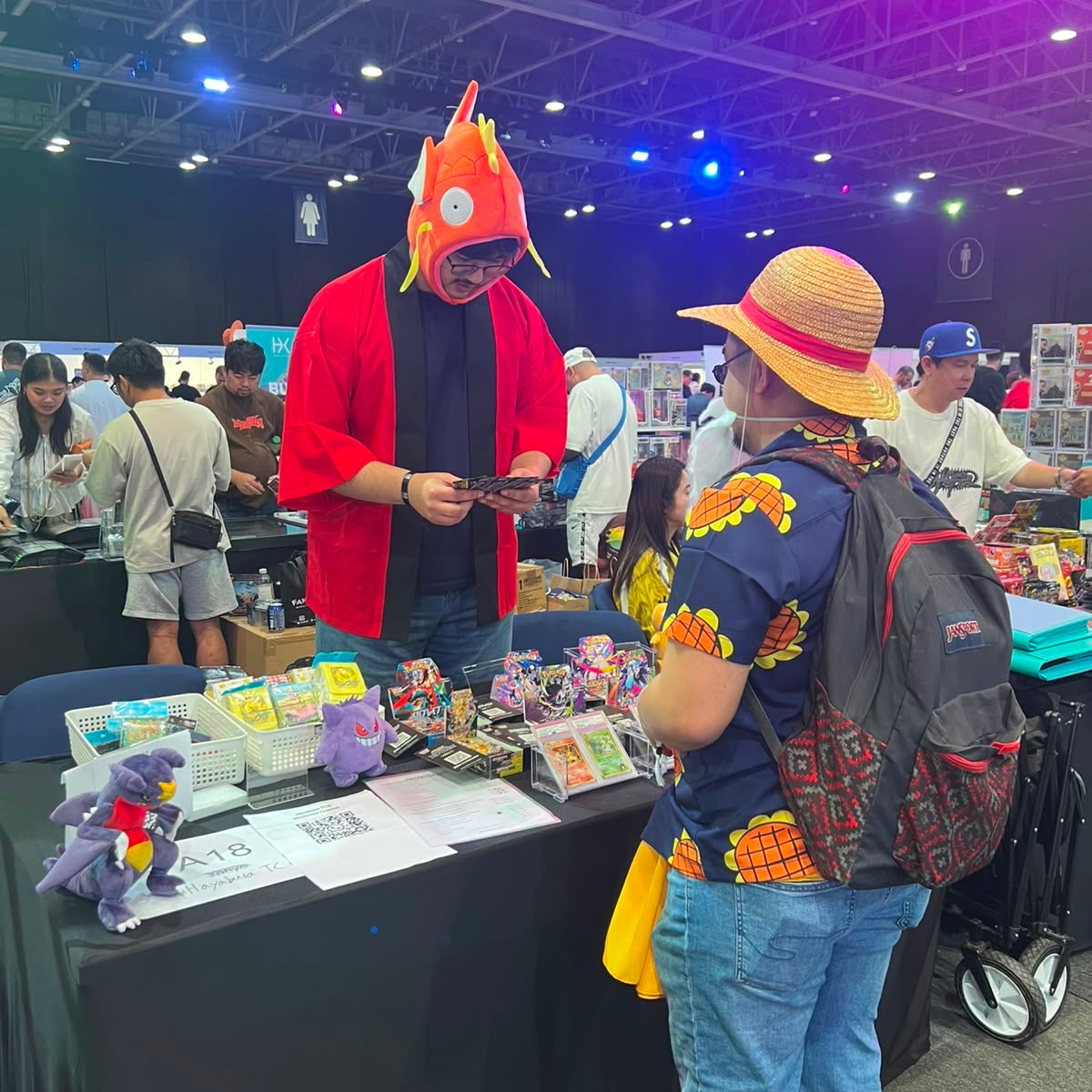 People at a convention with a vendor table displaying items.